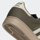 Championes Adidas Superstar II de diseño urbano, con parte superior de cuero nobuk en color verde oliva, franjas laterales y detalle en talón en color crema, y suela de goma en tono arena.