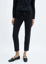 Jeans mom fit de tiro alto en color negro, confeccionados en denim elástico con diseño de cinco bolsillos, trabillas para cinto y cierre frontal con cremallera y botón.
