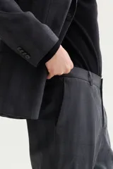 Pantalón de traje gris con sutil patrón a cuadros, corte slim fit con raya marcada en las piernas, bolsillos laterales y bolsillos traseros ribeteados.