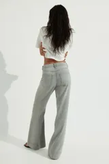 Jean de denim rígido color gris claro lavado, tiro superalto, pierna ancha y corte holgado. Presenta bolsillos parche grandes en la parte delantera y bolsillos parche en la parte trasera. El bajo es largo y sin dobladillo.