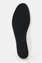 Zapatilla deportiva estilo blucher de color blanco, con cordones del mismo tono, pespuntes decorativos y suela plana con base negra.
