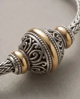 Pulsera de plata 925 y lámina de oro 18k de la línea Hindi, con diseño trenzado y una esfera central decorada con detalles tallados.