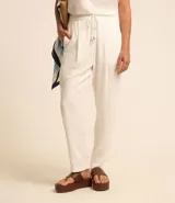 Pantalón celeste de corte recto, confeccionado en tejido de lino y viscosa. Presenta cintura elástica con lazo ajustable, bolsillos laterales y pliegues frontales.