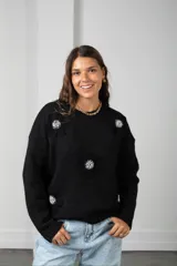 Buzo tejido de punto color negro, con diseño oversize, cuello redondo y apliques florales en relieve con centro de cuentas brillantes.