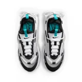 Championes Nike Air Max Furyosa, color gris, blanco y negro, con detalles plateados. Capellada de malla y cuero sintético, con cordones blancos y sistema de ajuste con cordones elásticos en el talón. Entresuela de espuma con tecnología Air Max visible en la parte trasera.