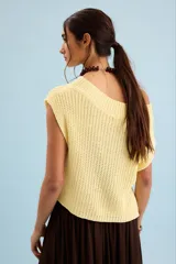 Chaleco de tejido de punto en color amarillo claro, con escote bote amplio que permite usarlo con un hombro al descubierto, de corte holgado y sin mangas.