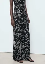 Pantalón de tiro medio confeccionado en mezcla de lino y viscosa, con diseño recto, bolsillos laterales, trabillas y cierre de botón y cremallera. Presenta un estampado de flores y hojas de estilo lineal en contraste.