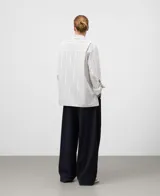 Camisa de algodón orgánico, blanca con finas rayas verticales negras. Presenta un corte oversize, cuello solapa, manga larga con puño y bolsillo en el pecho.