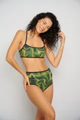 Conjunto de bikini con estampado abstracto en tonos verdes y amarillos, con contorno negro. El corpiño es de corte deportivo y la bombacha es de tiro alto.