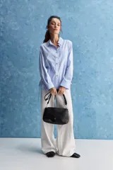 Camisa celeste de calce relajado, con cuello camisero, bolsillo aplicado en el pecho y mangas largas con puños abotonados. Cuenta con lazos ajustables en los laterales para fruncir y regular la silueta.