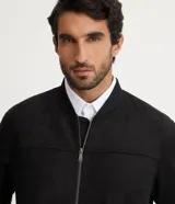 Chaqueta bomber azul marino lisa, con cierre frontal, cuello redondo y bolsillos laterales.