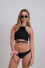 Conjunto de bikini negro con corpiño halter con detalle de flor y bombacha clásica.
