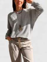 Sweater de punto con diseño oversize y corte relajado, confeccionado en una mezcla de viscosa y lana. Presenta cuello redondo, mangas largas y un largo asimétrico con la parte trasera más extensa.