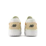 Championes urbanos New Balance modelo BBW550ST, color blanco con detalles en beige y mostaza, confeccionados en cuero sintético, con logo "N" característico en los laterales y suela de goma.