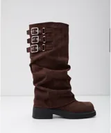 Botas de caña alta estilo slouchy en color marrón, confeccionadas en gamuza. Presentan tres correas horizontales con hebillas metálicas plateadas en la parte superior de la caña y una suela de goma negra con plataforma plana.