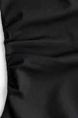 Top negro de punto, ajustado al cuerpo, con escote barco drapeado y frunces laterales.