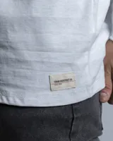 Remera de manga larga en color blanco, con cuello redondo y corte clásico. Presenta un pequeño detalle de etiqueta cosida en el puño de la manga.