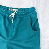 Short deportivo azul petróleo con cintura elástica ajustable con cordón y bolsillos laterales.