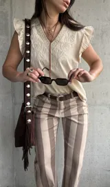 Musculosa de color beige con escote en V, mangas con volados y delicados bordados frontales.