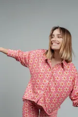 Camisa de manga larga color rosado con estampado de flores anaranjadas y blancas.