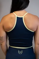 Musculosa deportiva de lycra color azul marino con ribetes y tirantes finos en color amarillo claro. Presenta un logo caligráfico en color amarillo claro en el pecho.