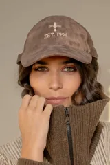 Gorra tipo baseball color chocolate con efecto desgastado y bordado frontal en hilo color crema que incluye un símbolo y la inscripción 'EST. 1994'.