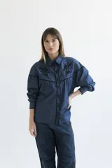 Camisa negra de manga larga con canesú estampado con diseño floral, cuello camisero y cierre frontal con botones.