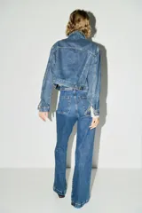 Jean de tiro alto con corte acampanado desde la rodilla. Presenta bolsillos tipo parche en la parte frontal y cierre con botón metálico.