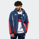 Campera de abrigo con capucha, diseño en bloques de color azul, rojo y blanco. Presenta cierre frontal, bolsillos laterales y el escudo del Club Nacional de Football junto al logo de Umbro en el pecho.