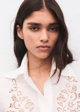 Camisa blanca de manga larga con detalles bordados calados en el frente y puños anchos.