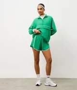 Bermuda deportiva tipo runner color verde, confeccionada en microfibra liviana. Presenta cintura elástica, short interno integrado para mayor seguridad y detalles de friso en color blanco en los bordes redondeados.