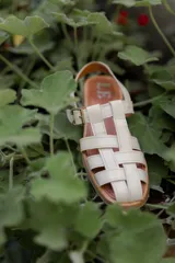 Sandalias de cuero con tiras entrecruzadas, suela plana y hebilla lateral.