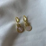 Par de aros dorados con argolla de strass, dije de flor calada y dije colgante redondo de nácar.