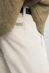 Pantalón chino de corte ajustado, color beige, con bolsillos laterales y bolsillos traseros de vivo. Cuenta con cierre frontal de cremallera y botón.