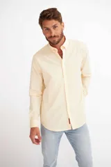Camisa de hombre color crema, de corte clásico, con cuello abotonado y mangas largas.