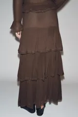 Falda midi color marrón chocolate, de tiro medio, con volantes en el mismo tejido y aplicación de abalorios. Cierre lateral con cremallera oculta en costura.