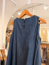 Vestido corto de denim azul sin mangas, con corte evasé amplio y fluido.