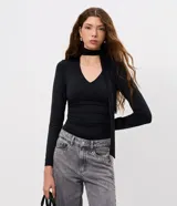 Blusa entallada de microfibra color negro, con escote en V, mangas largas y detalle de frunces en los laterales. Incluye un lazo integrado en el cuello que permite anudarlo.