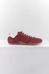 Zapatillas deportivas marrones de gamuza con cordones blancos y detalles en cuero blanco en el talón.