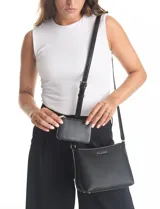 Cartera tipo bandolera Tahari color azul, con diseño estructurado y cierre metálico superior. Incluye una correa larga regulable y un mini monedero independiente enganchado a la misma. Presenta logo metálico frontal y herrajes plateados.