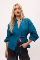 Chaqueta azul con cuello mao, mangas largas abullonadas y lazo en la cintura.