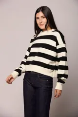 Buzo tejido de punto con diseño de rayas horizontales anchas en color blanco y negro, cuello redondo y mangas largas con puños ajustados.