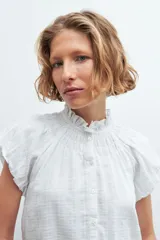Camisa blanca de manga corta con cuello mao y detalle de punto smock.