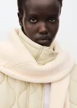 Campera acolchada de diseño oversize en color beige, con cuello alto, cierre frontal de cremallera y botones, y bolsillos laterales.