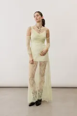 Vestido largo blanco de encaje con diseño asimétrico, tirante fino en un hombro y falda transparente.