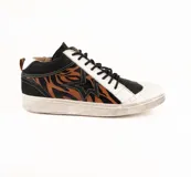 Zapatilla de cuero vacuno con diseño de caña media, combinando paneles en negro, blanco y un estampado animal print de tigre en tonos marrones. Presenta un aplique lateral en forma de estrella, cordones negros y suela de goma con efecto desgastado.