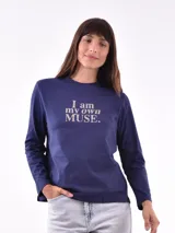 Remera de manga larga color azul marino con cuello redondo y estampado frontal que dice "I am my own MUSE." en color beige.