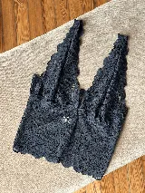 Topcito tipo bralette de encaje negro con escote en V profundo y tirantes anchos. El encaje es elastizado para un ajuste cómodo.