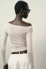 Top de manga larga confeccionado en tejido de algodón, con diseño de escote asimétrico y corte ajustado al cuerpo.