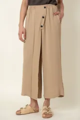 Pantalón ancho color beige, con cintura elastizada, bolsillos laterales y detalle de botones decorativos.